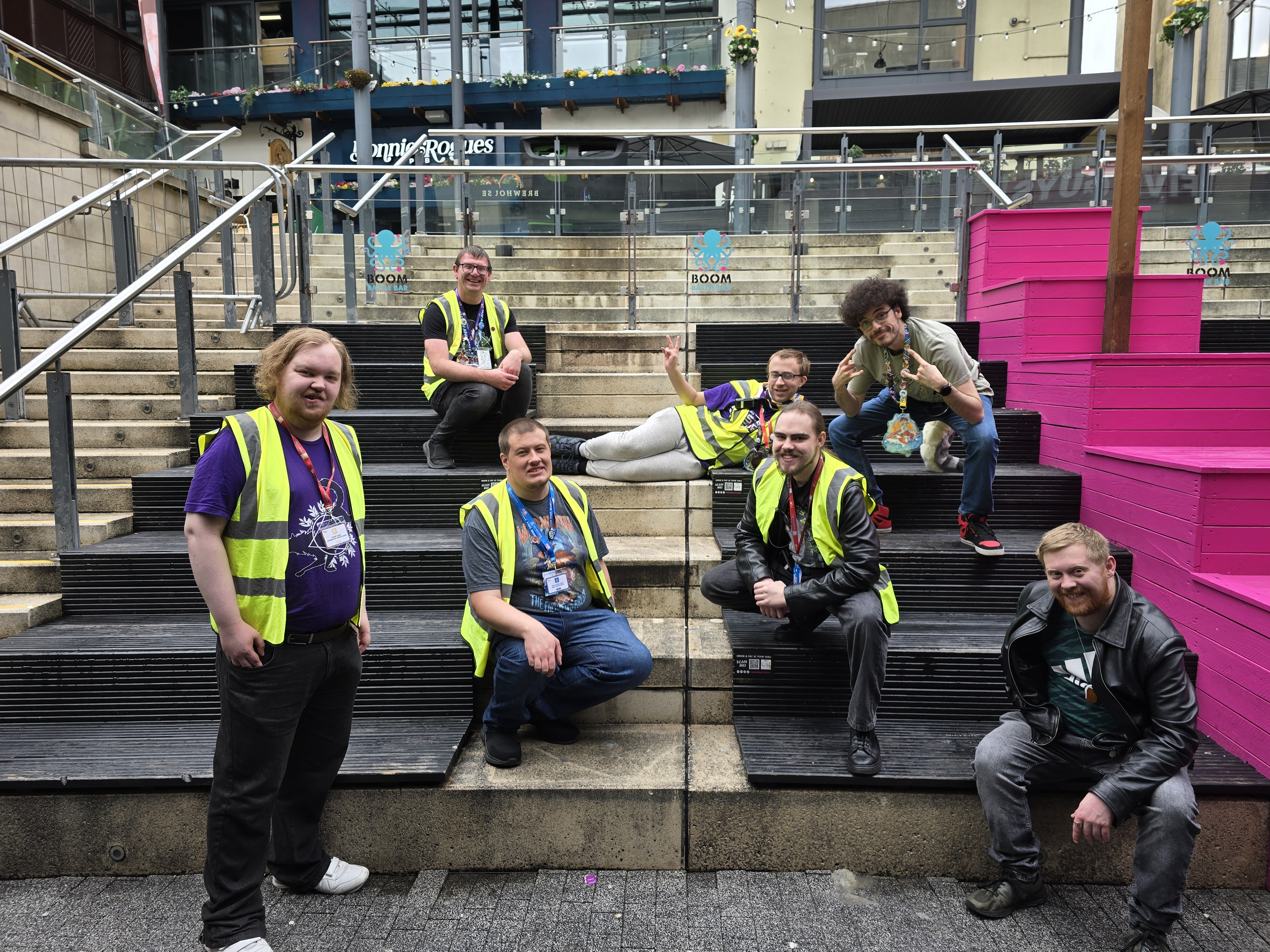 Photo of FurTheMoment staff, some with high visibility, posing for camera - outside on stair seating